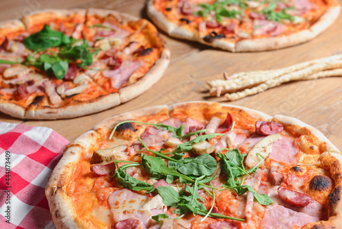 Three different pizzas on wooden table. Freshly baked traditional Italian Pizza over wooden background.