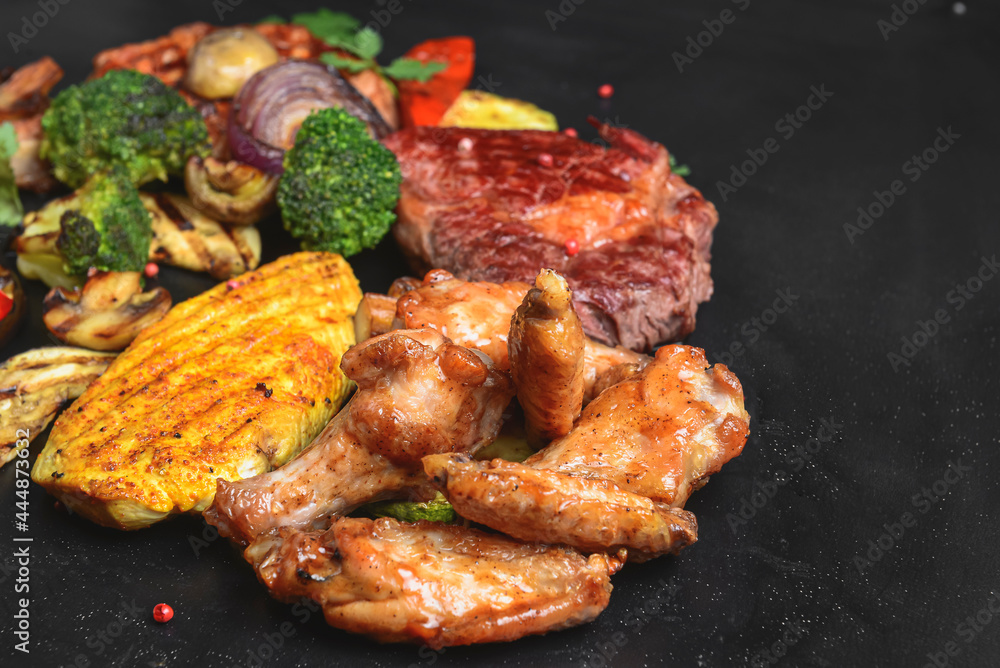 Hot spicy fried set. Grilled chicken, pork and beef over black background, with BBQ vegetables.