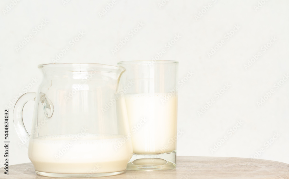 Pure milk drinks in clear jars and bottles are naturally healthy foods placed on a desk wood on a blue background Pure milk drinks in clear jars and bottles are naturally healthy foods placed on a desk wood on a blue background