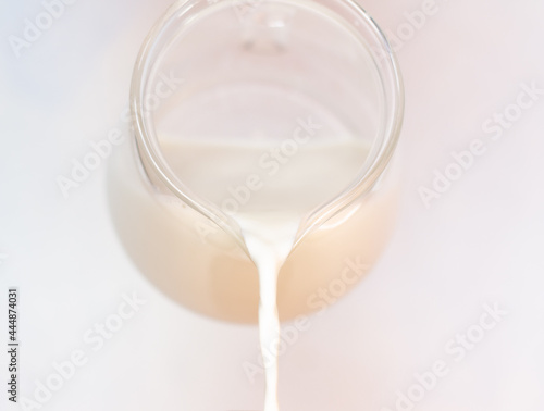 Select focus pouring pure milk drinks from the bottle in clear jars are naturally healthy foods placed on a blue background