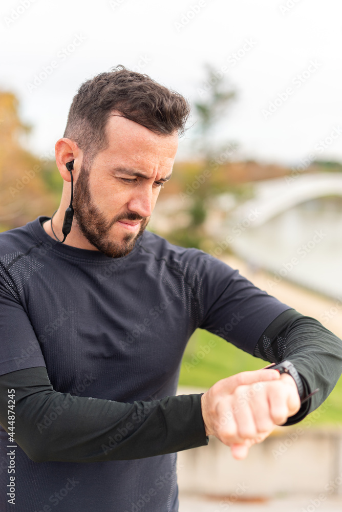Young runner man with headphones training and checking stopwatch. Young runner man with headphones training and checking stopwatch.