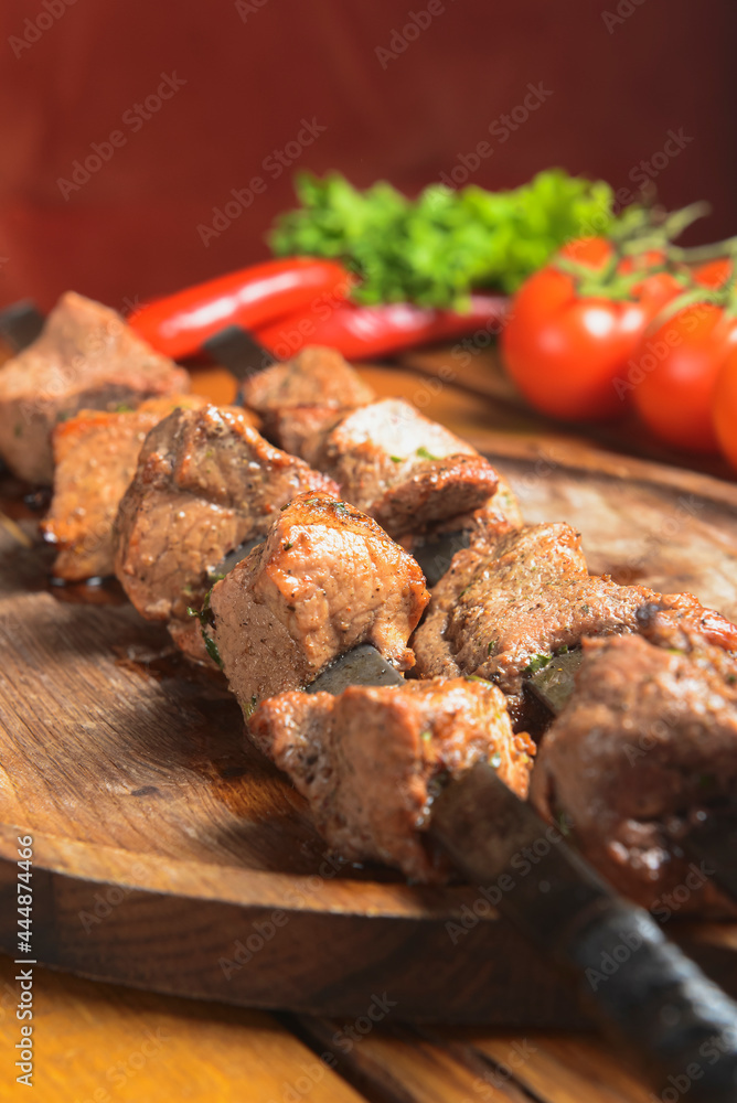 Marinated shashlik cooked on a barbecue grill over charcoal. Shashlik or Shish kebab served on a wooden board