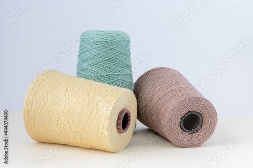 Pastel color bobbins of wool yarn for hand and machine knitting on a white background