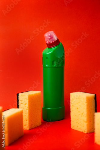 green bottle with cleaning agent and cleaning sponges on a red background photo
