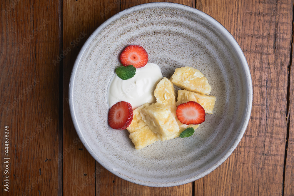 Vanilla cream dessert with sour cream and fresh organic strawberry. Served in a traditional bowl.