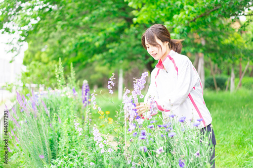 庭で花の世話をする若い女性