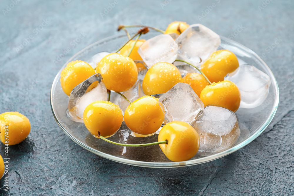 Plate with tasty sweet cherries and ice cubes on color background Plate with tasty sweet cherries and ice cubes on color background