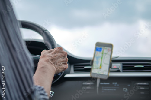 A woman drives a car using the navigator in a mobile phone