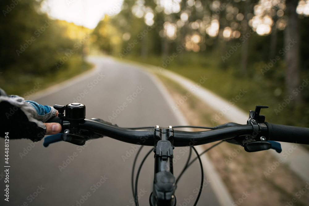 Asphalt bike path for bike riders. Concept of infrastructure for bikers. A cyclist holds a bicycle handlebar with his hand in glove. Asphalt bike path for bike riders. Concept of infrastructure for bikers. A cyclist holds a bicycle handlebar with his hand in glove.