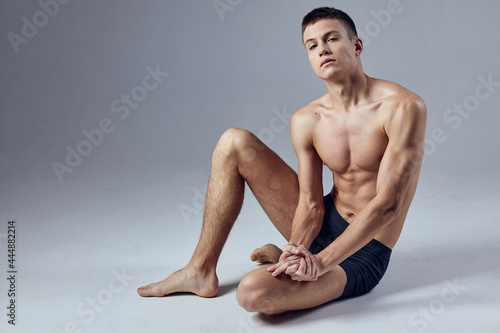 man with a pumped body posing sitting on the floor 