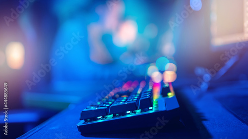 Closeup keyboard professional cyber gamer studio room with neon color blur background, soft focus