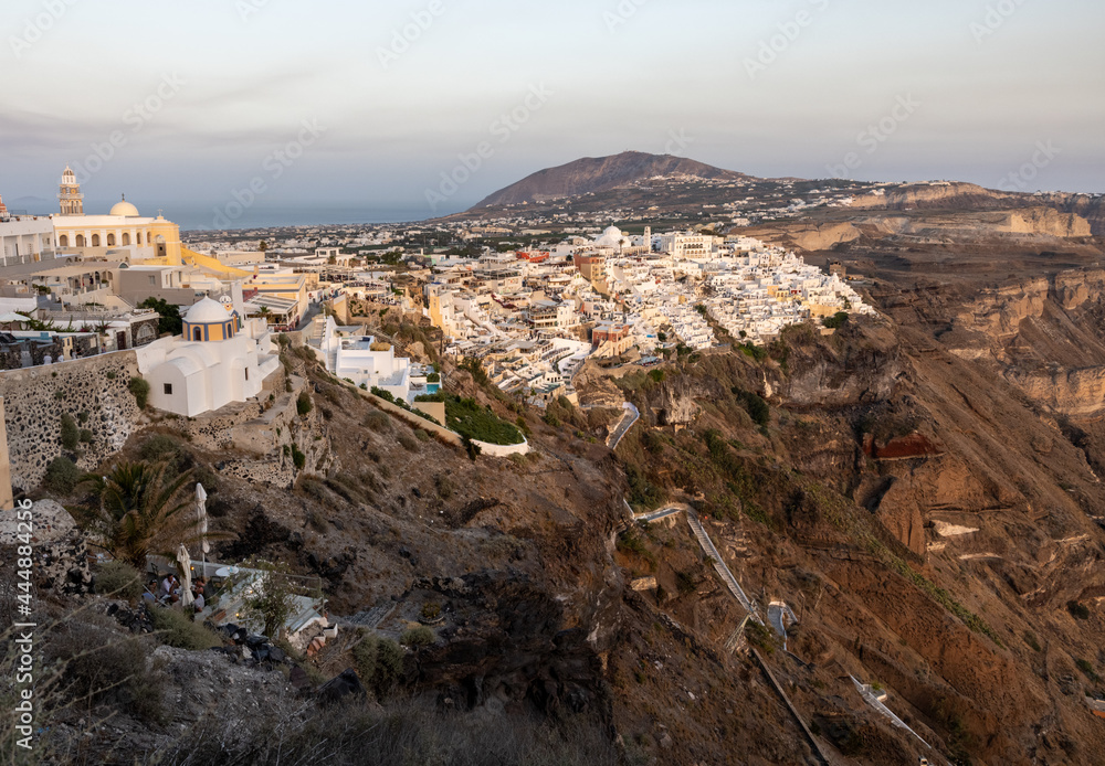 The whitewashed town of Fira in warm rays of sunset on Santorini island, Cyclades, Greece
