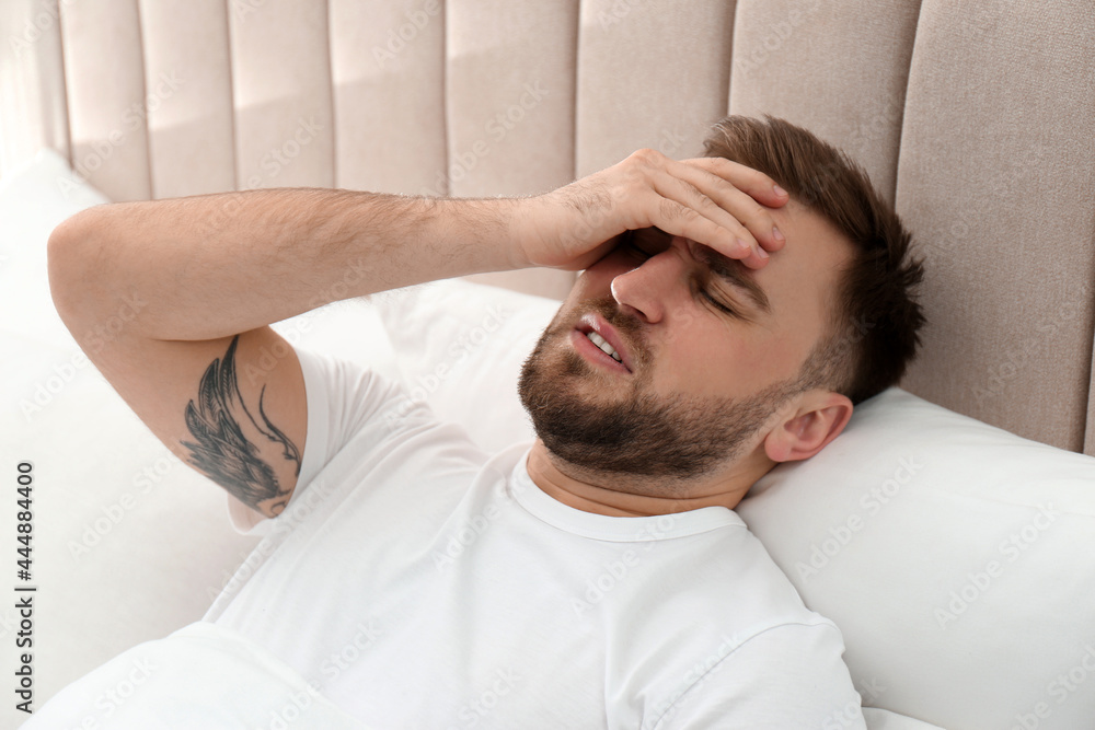 Young man suffering from migraine in bed Young man suffering from migraine in bed