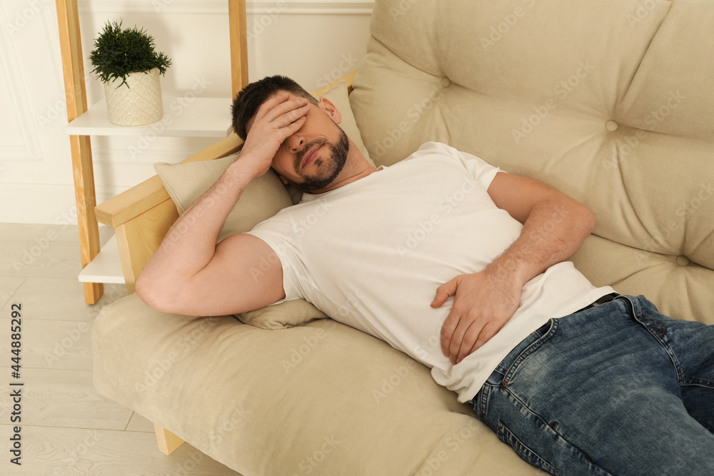 Man suffering from pain in lower right abdomen on sofa at home. Acute appendicitis Man suffering from pain in lower right abdomen on sofa at home. Acute appendicitis