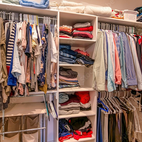 Square Man and woman clothes in a shared walk in closet with shelves and hanging rods