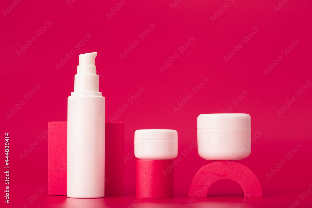 White cosmetic tube and jar on geometric shapes for cosmetic products presentation against dark pink background. Concept of skin care products with hydrating, glowing or anti aging effect White cosmetic tube and jar on geometric shapes for cosmetic products presentation against dark pink background. Concept of skin care products with hydrating, glowing or anti aging effect