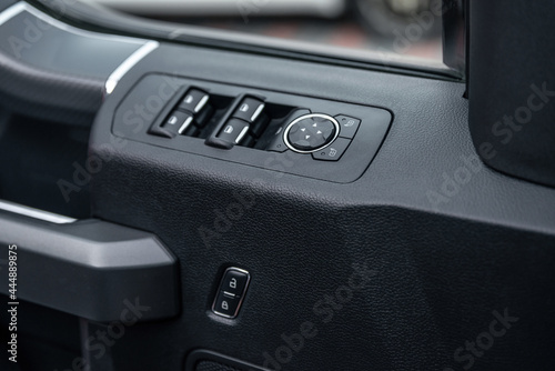 Mirror control knob and window control panel in a modern car. Automatic car window controls and details. Car door lock unlock button. Selective focus.