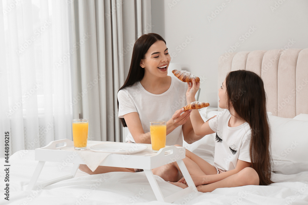 Young mother and her daughter having breakfast on bed at home Young mother and her daughter having breakfast on bed at home