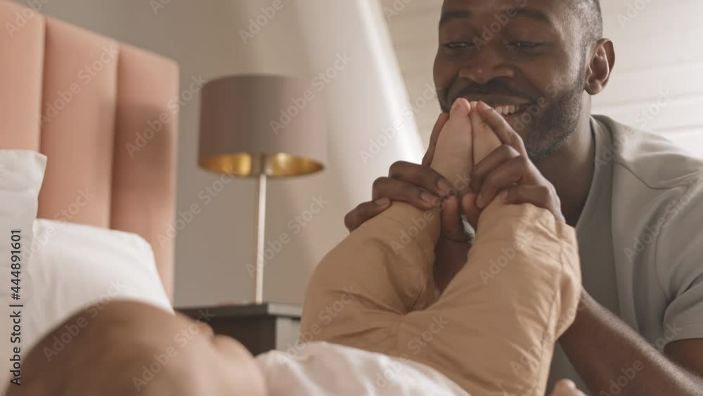 Chest-up of happy African man kissing and clapping feet of cropped unrecognizable baby at home, smiling and admiring child Chest-up of happy African man kissing and clapping feet of cropped unrecognizable baby at home, smiling and admiring child