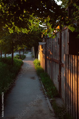 Beautiful sunset in the village. Sunny quiet evening. Cozy place. Old street.Wooden Russian fence