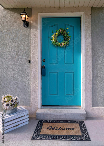 Vertical Light blue front door with wreath and portico at the facade of residential home