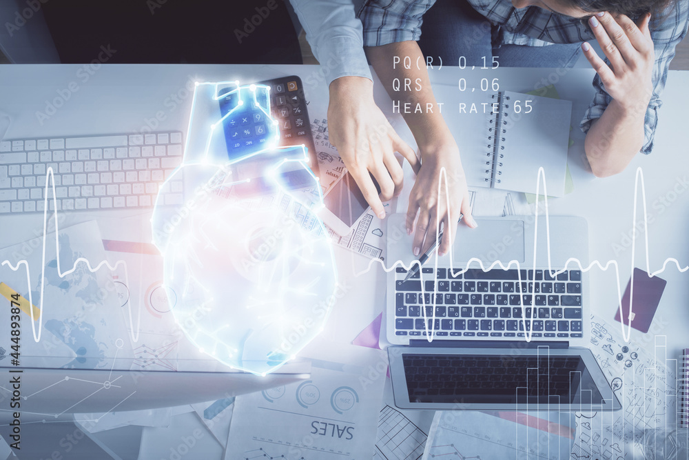 Double exposure of man and woman working together and heart hologram drawing. Computer background. Top View. Double exposure of man and woman working together and heart hologram drawing. Computer background. Top View.