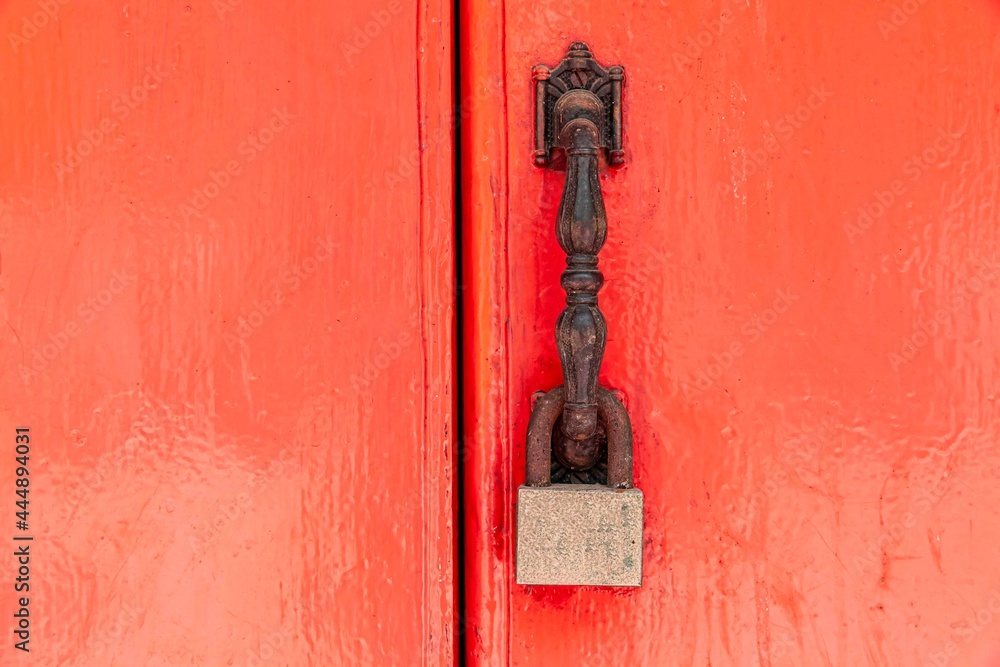 The padlock hangs on the red wooden door The padlock hangs on the red wooden door