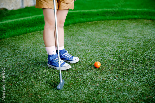 Cute preschool girl playing mini golf with family. Happy toddler child having fun with outdoor activity. Summer sport for children and adults, outdoors. Family vacations or resort. photo