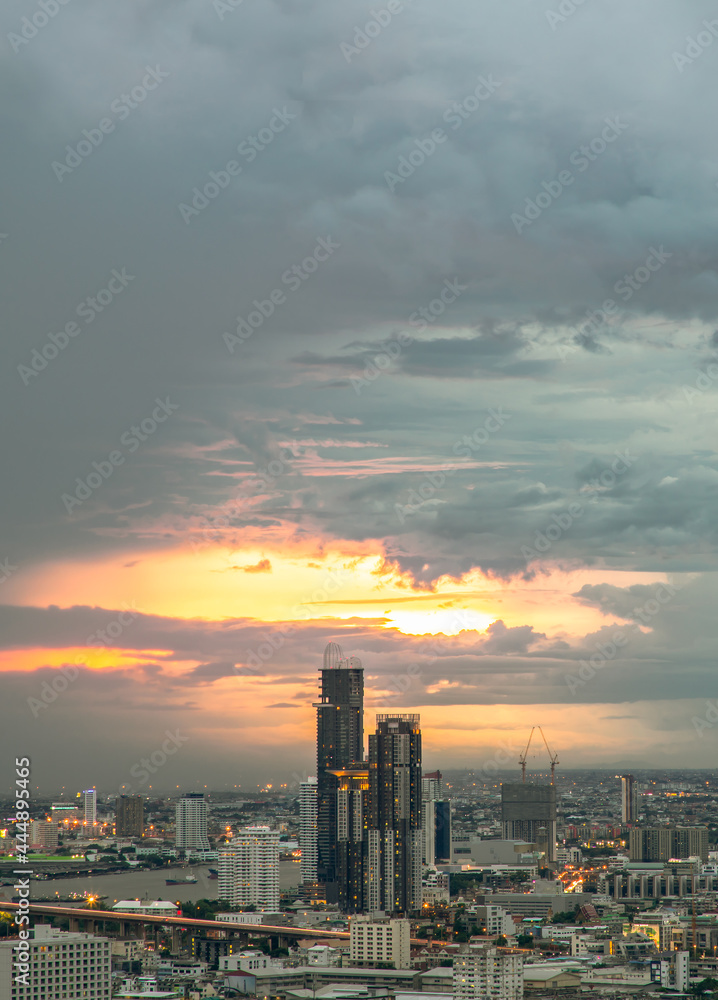 Fototapeta premium Bangkok, Thailand - 07 Jul 2021 : Aerial view of Beautiful sunset over large metropol city in Asia. There are prominent and isolated high-rise buildings along the Chao Phraya River. Selective focus.