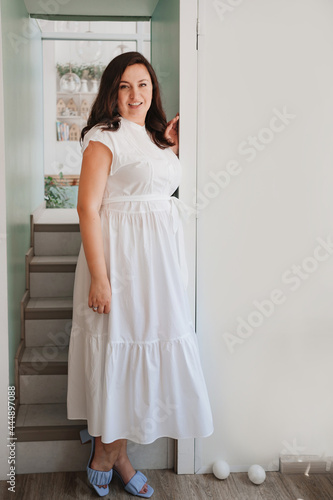 attractive woman in white dress stands in the doorway by the stairs.  © andrey