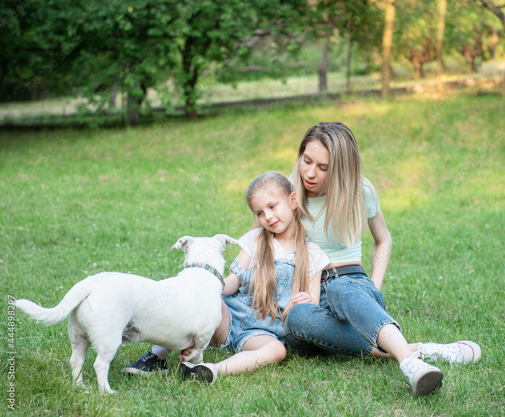 Obraz premium Woman and little girl playing with a dog