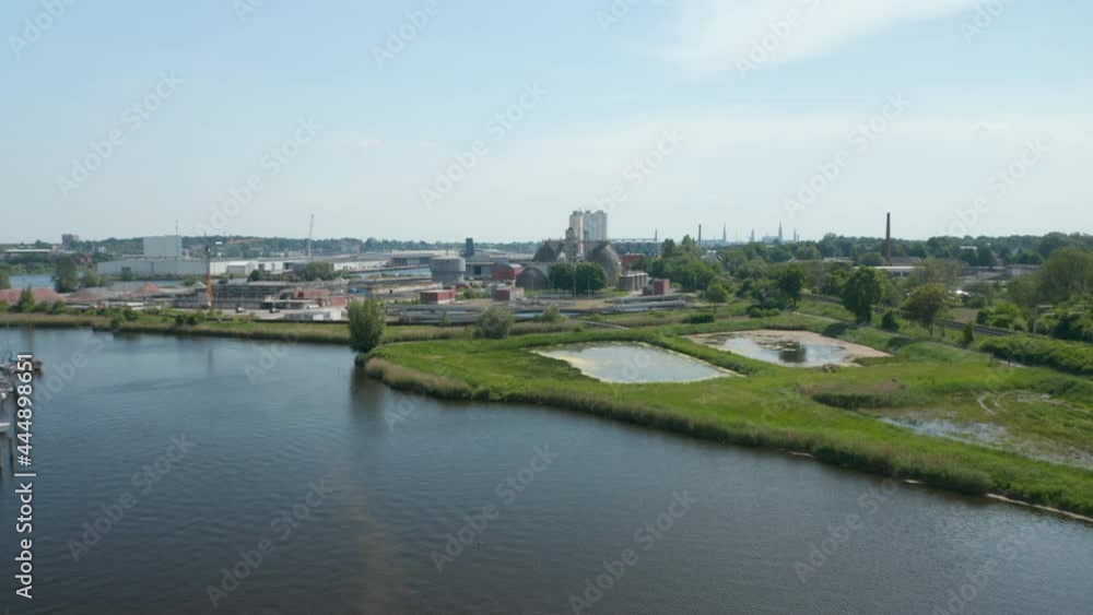 Forwards fly above river. Heading to industrial area. City skyline in distance. Luebeck, Schleswig-Holstein, Germany Forwards fly above river. Heading to industrial area. City skyline in distance. Luebeck, Schleswig-Holstein, Germany