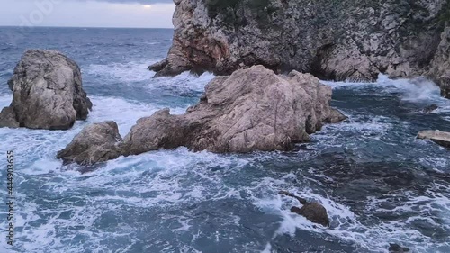 Waves Crashing on rock in golden hour with sunbeam and clouds