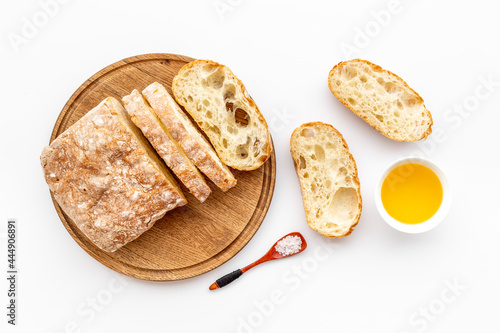 Sliced bread ciabatta with oil on cutting board, top view