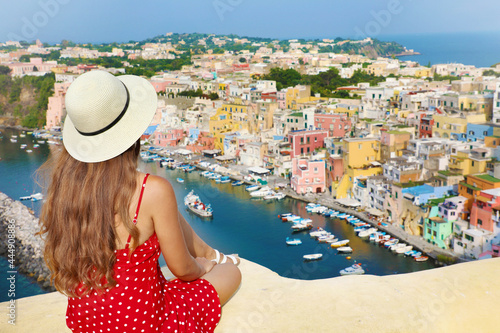 Beautiful young female tourist enjoying view of Marina di Corricella harbor and the village of Procida Island, Italy. Procida is the Italian Capital of Culture 2022. photo