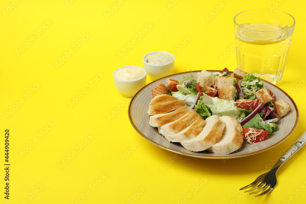 Concept of tasty eating with Caesar salad on yellow background Concept of tasty eating with Caesar salad on yellow background