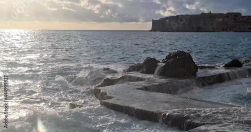 Waves Crashing on rock in golden hour with sunbeam and clouds