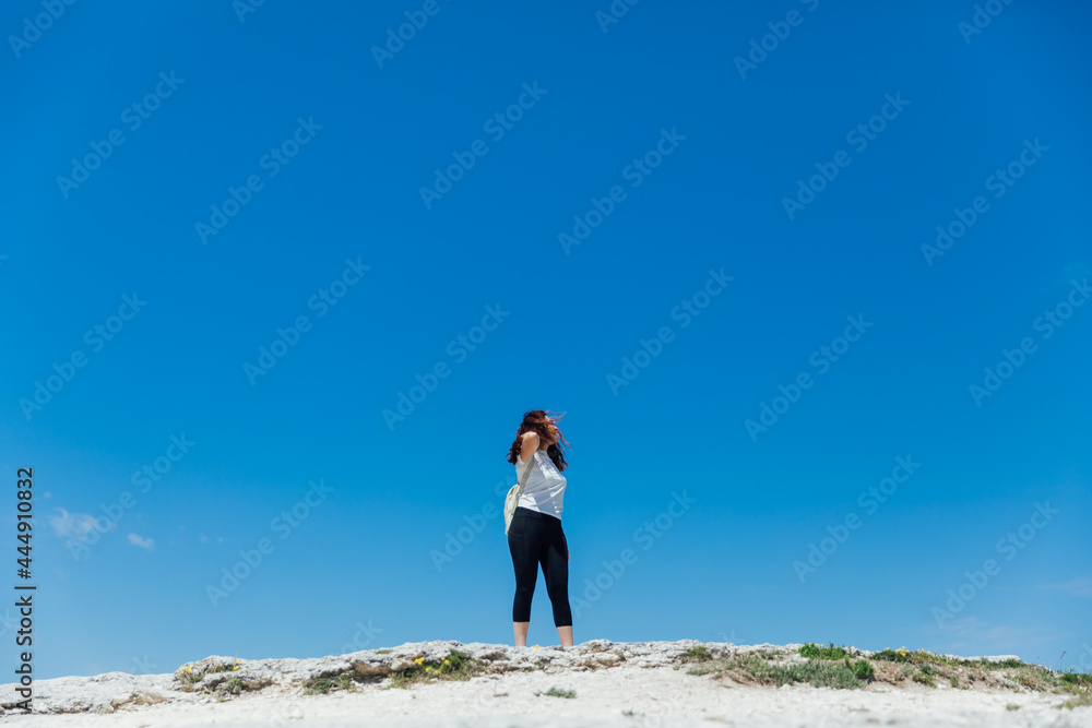 woman standing on a cliff looking at the sky of the journey