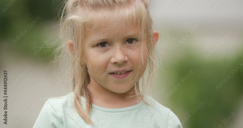 close up of adorable blonde girl smiling, covering face with hands while holding strawberries outside in backyard