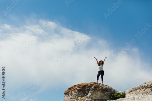 brunette woman standing on a cliff looking at the nature of the journey