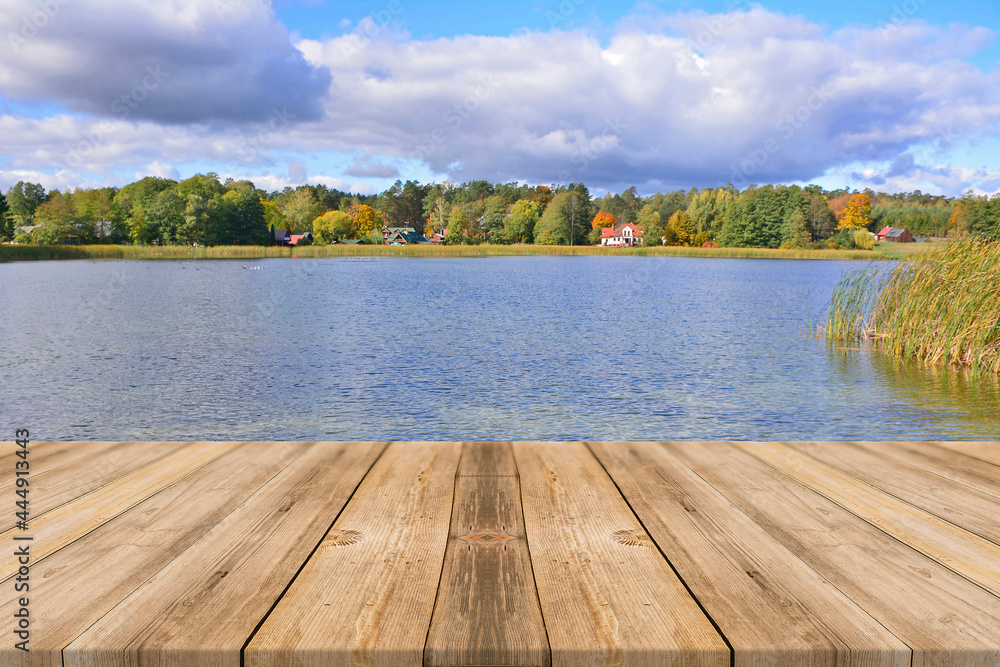 Wood floor perspective on the lake and village on the autumn forest and blue sky backgrounds