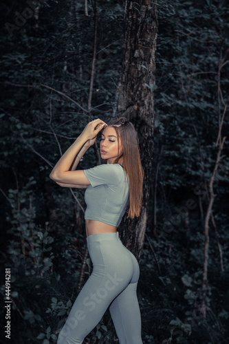 Beautiful sexy woman glamor fashion model wear stylish clothes fall collection forest trees nature in the park romantic. Female perfect body poses.