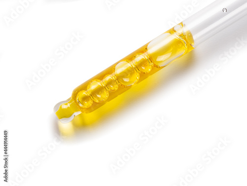 Glass cosmetic dropper with yellow serum.