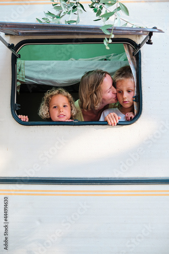 a mother and her children looks trhough the window of her caravan