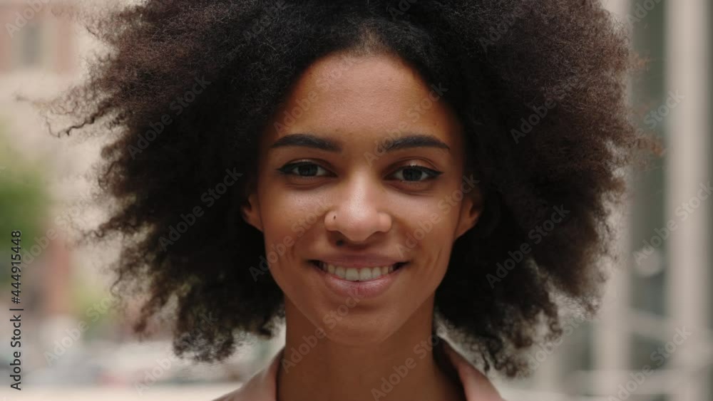 Portrait view of the young African American curly woman spending her day at the city and feeling great. People emotions face portrait concept. Portrait view of the young African American curly woman spending her day at the city and feeling great. People emotions face portrait concept.