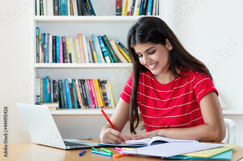 Laughing hispanic female student learning language online using computer