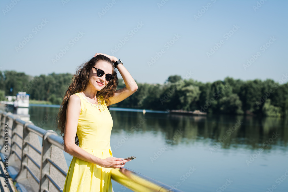 Beautiful girl in a yellow dress walks in a summer park