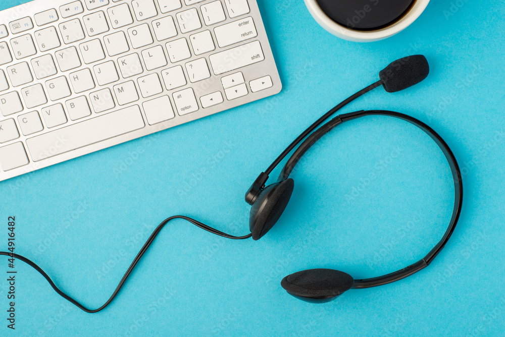 Top view photo of black headset white keyboard and cup of coffee on isolated pastel blue background Top view photo of black headset white keyboard and cup of coffee on isolated pastel blue background