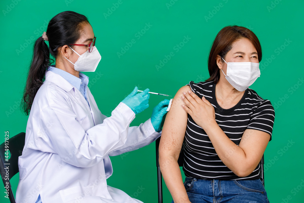 Asian female doctor in white gown wearing mask holding syringe injecting Covid 19 vaccine to patient. Concept for Covid 19 vaccination