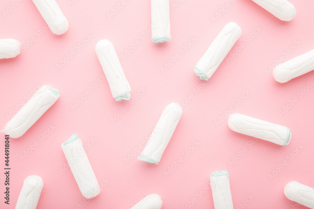 Many new white sanitary tampons on light pink table. Pattern background. Pastel color. Closeup. Female hygiene. Top down view. Many new white sanitary tampons on light pink table. Pattern background. Pastel color. Closeup. Female hygiene. Top down view.